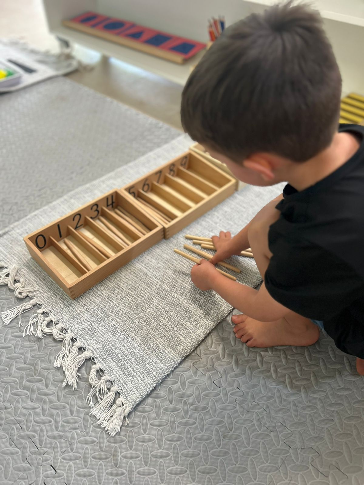 Child sorting spindles in a Montessori number box