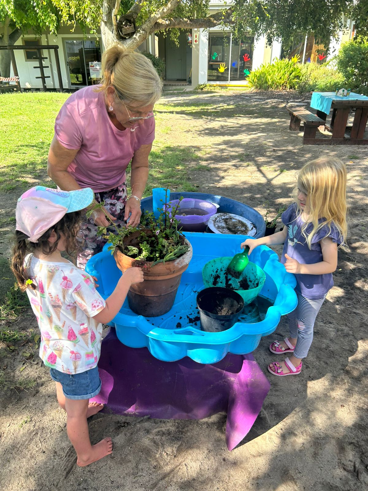 Educator and children at the outdoor water and plant table