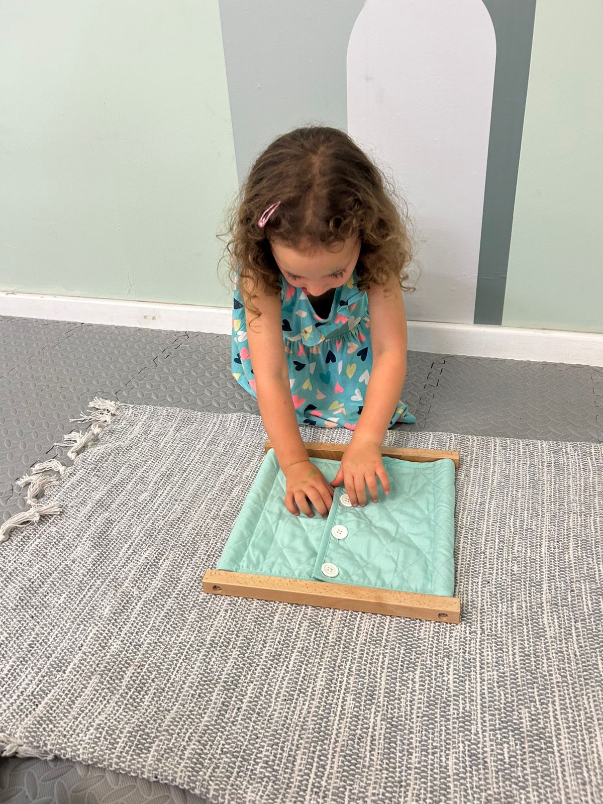 Child practising buttoning on a Montessori dressing frame