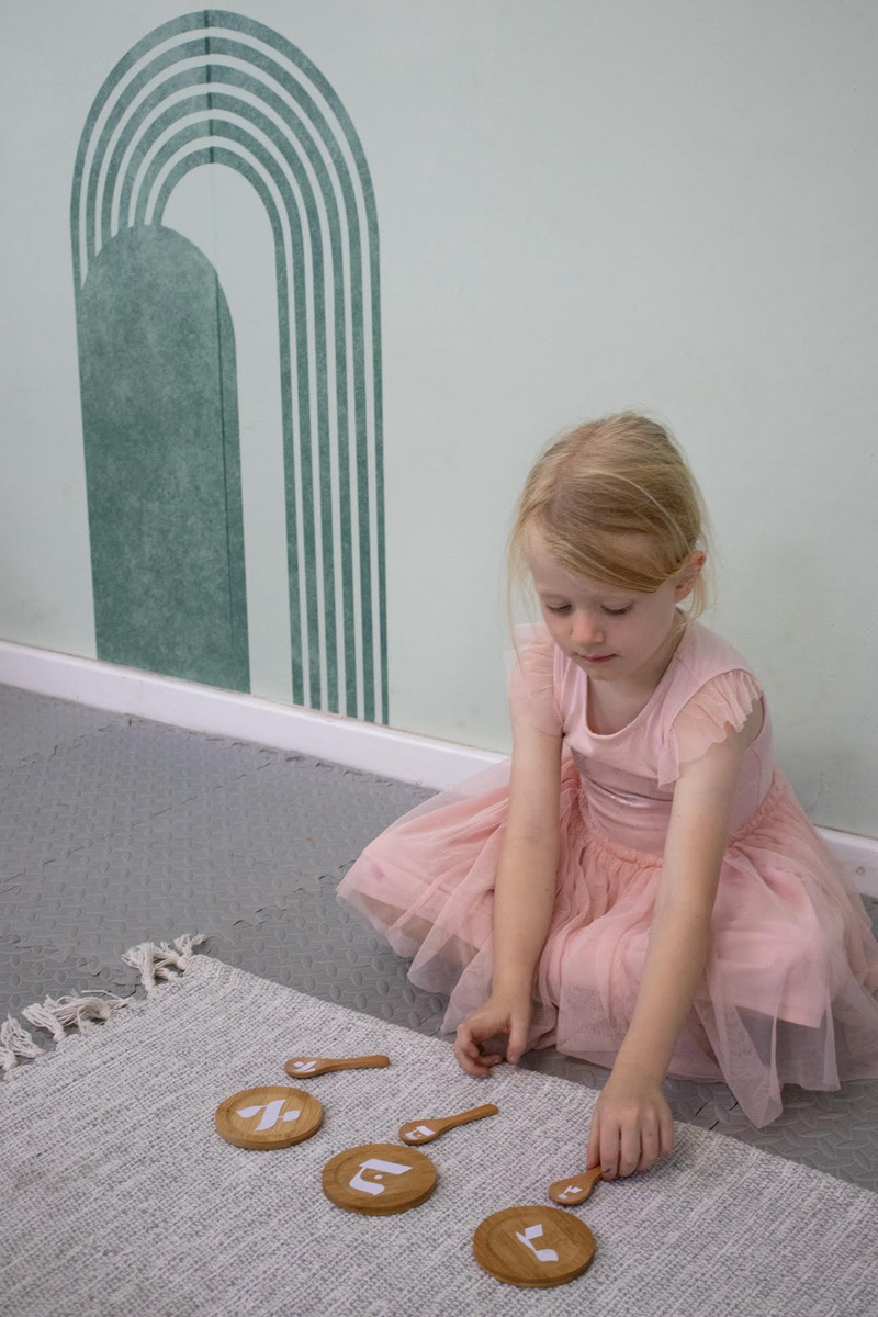 Child learning Hebrew letters with wooden tiles